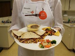 image of a student wearing an Eat Real! apron holding plate of food